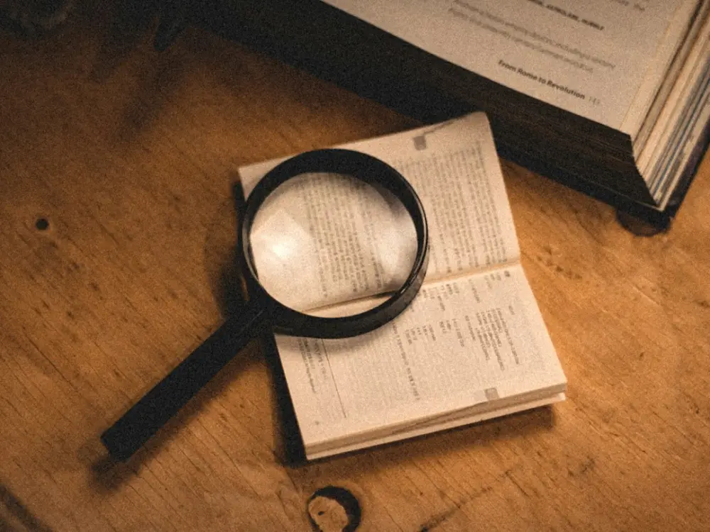 A magnifying glass sitting on top of an open book, illustrating comparing purchase evidence clearly
